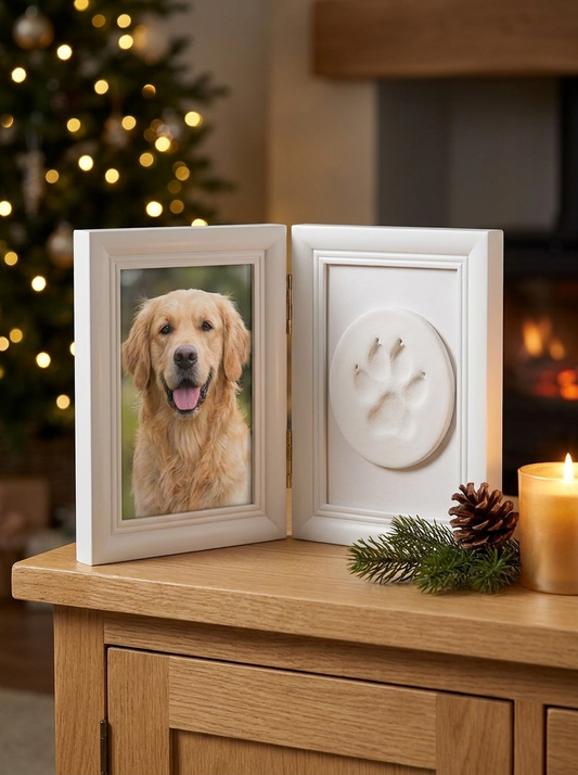 Cadre double blanc avec photo d'un chien et empreinte de patte, posé sur un buffet en bois à Noël